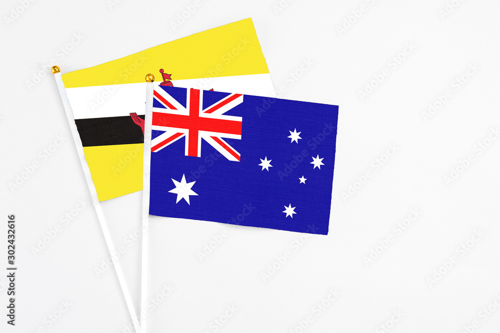 Fototapeta premium Australia and Brunei stick flags on white background. High quality fabric, miniature national flag. Peaceful global concept.White floor for copy space.
