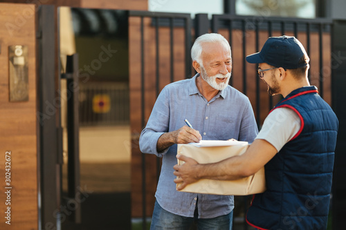 Happy mature man signing for his package delivery.