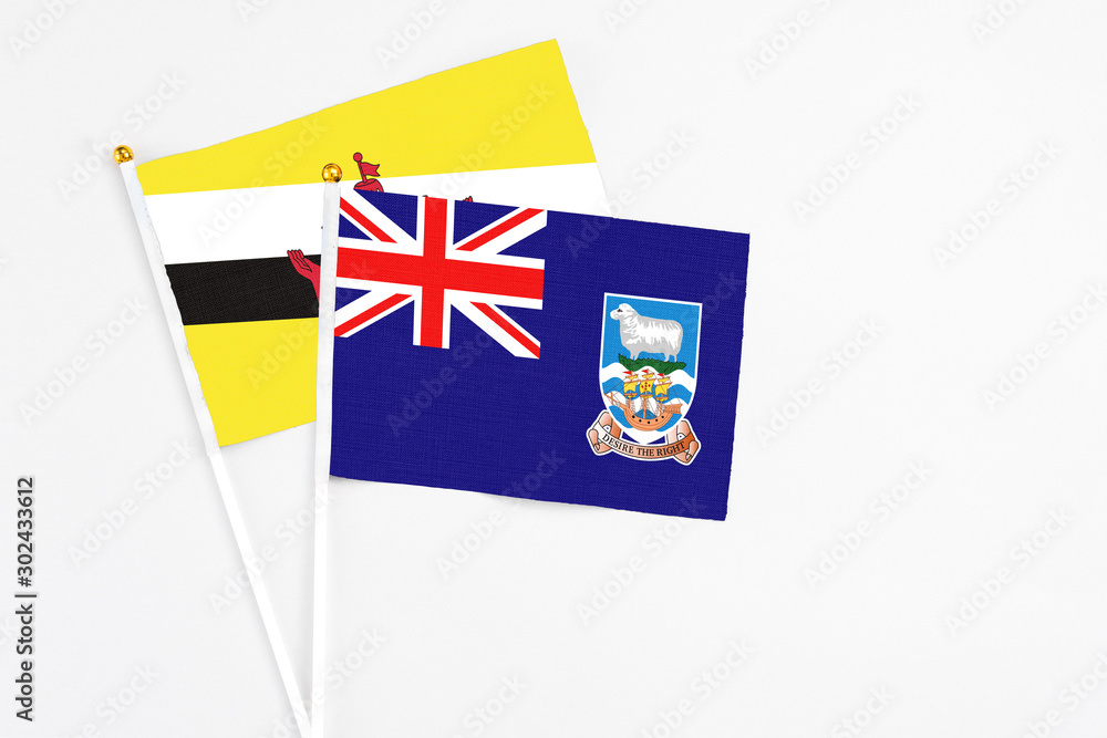 Falkland Islands and Brunei stick flags on white background. High quality fabric, miniature national flag. Peaceful global concept.White floor for copy space.