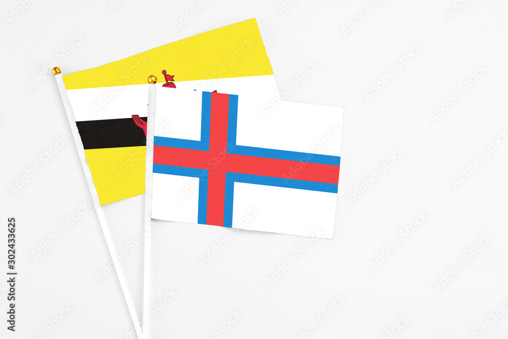 Faroe Islands and Brunei stick flags on white background. High quality fabric, miniature national flag. Peaceful global concept.White floor for copy space.