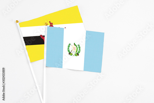 Guatemala and Brunei stick flags on white background. High quality fabric, miniature national flag. Peaceful global concept.White floor for copy space.