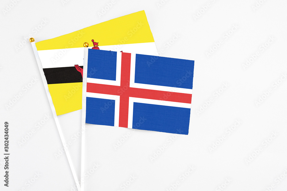 Iceland and Brunei stick flags on white background. High quality fabric, miniature national flag. Peaceful global concept.White floor for copy space.