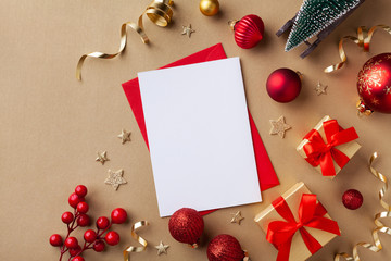 Empty paper blank for Christmas or New year greeting card. Gift boxes, holiday decorations, small fir tree on golden background top view. Flat lay.