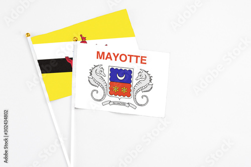 Mayotte and Brunei stick flags on white background. High quality fabric, miniature national flag. Peaceful global concept.White floor for copy space.