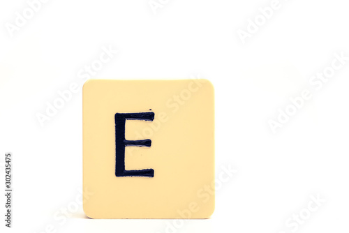 Dark letter E on a pale yellow square block isolated on white background
