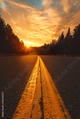 Fototapeta Naklejka Na Ścianę i Meble -  Road to the sunset. Asphalt road in the forest and the sun