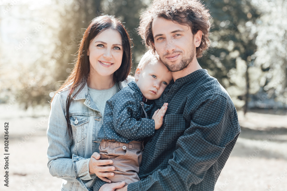 Fototapeta premium Family life. Portrait of parents and their son on the background of nature. Walk in park.