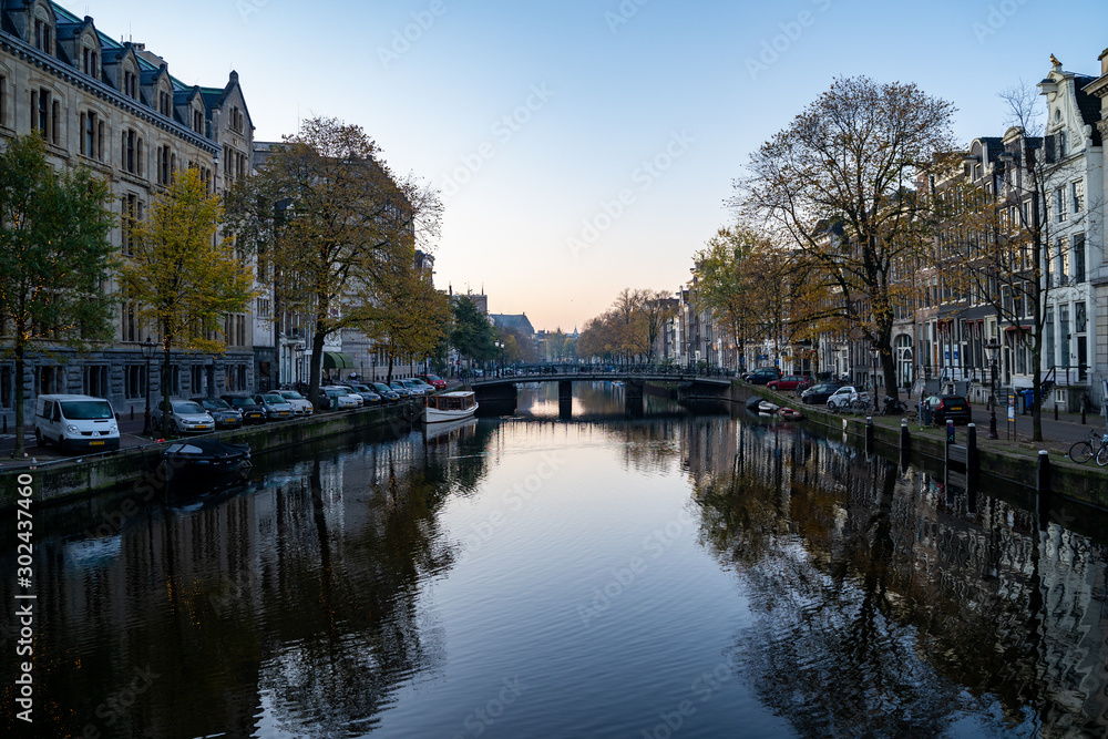 Amsterdam, Netherlands - Buildings and house boats along canal during an early autumn fall morning in the Jordaan neighborhood