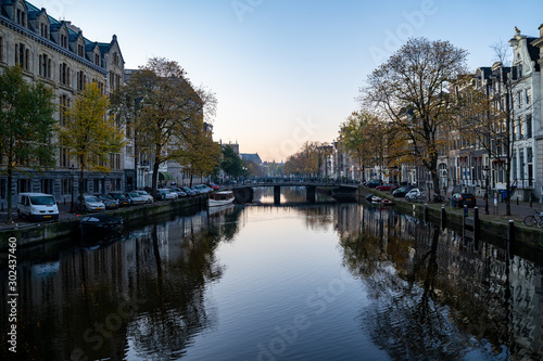 Amsterdam, Netherlands - Buildings and house boats along canal during an early autumn fall morning in the Jordaan neighborhood © MelissaMN