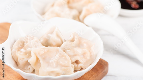 Fresh, delicious boiled pork, shrimp gyoza dumplings on white background with soy sauce and chopsticks, close up, lifestyle. Homemade design concept.