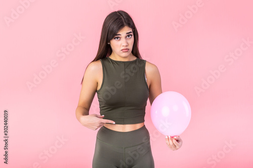 Beautiful young woman holding a pink balloon , feeling bloated concept , Woman having abdominal pain isolated on white