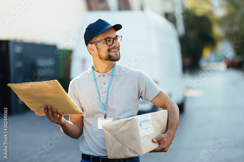 Happy courier looking for right address while making home delivery.