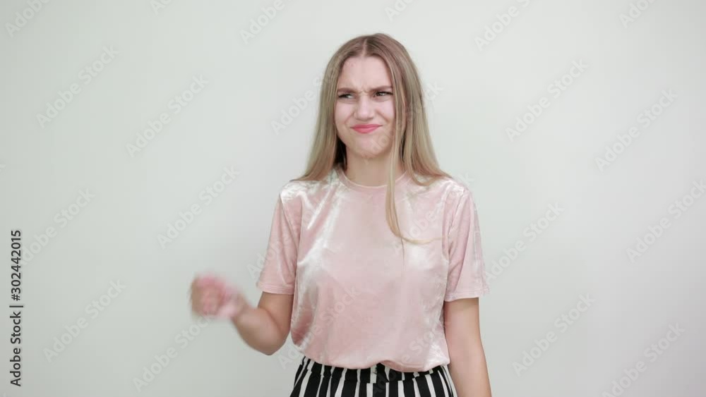 Caucasian attractive girl over white wall making unimportant gesture while lifting the shoulders wearing pastel pink shirt Caucasian attractive girl over white wall making unimportant gesture while lifting the shoulders wearing pastel pink shirt