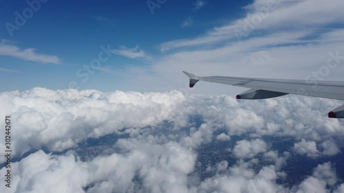 London, UK - August 2019: Wing of an airplane flying over the clouds over London