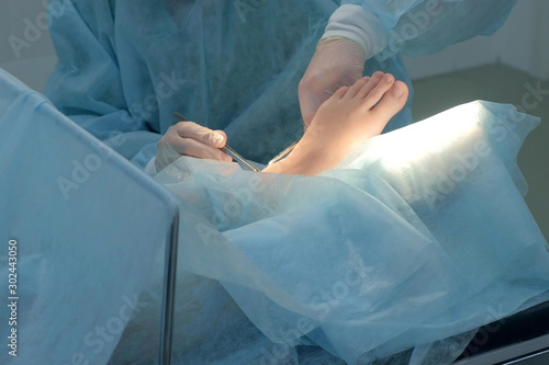 Wallpaper Mural Surgeon man making surgery of removal ankle hygroma on leg in hospital in operating room, hands closeup. Doctor using medical tools clamp and tweezers. Surgical treatment of hygroma. Torontodigital.ca