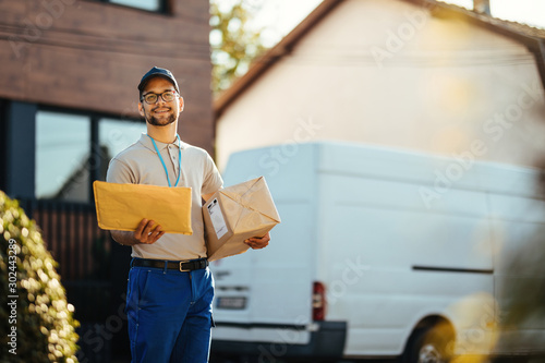 Canvastavla Young smiling postman delivery packages at residential district.