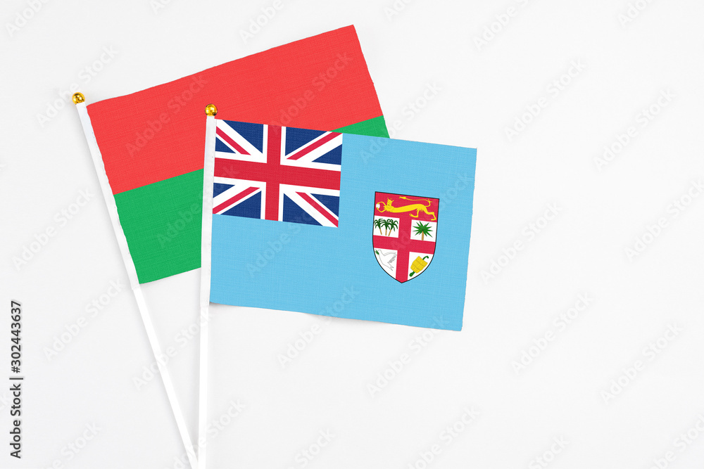 Fototapeta premium Fiji and Burkina Faso stick flags on white background. High quality fabric, miniature national flag. Peaceful global concept.White floor for copy space.