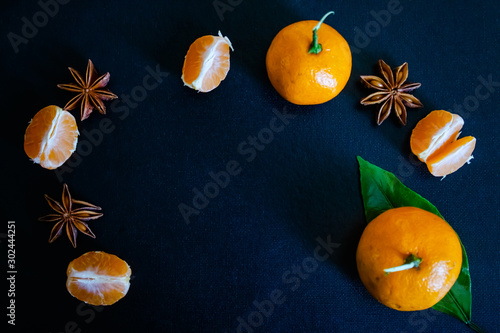 Dark textured christmas background with tangerine slices, citrus leaves, star anise and cinnamon sticks. Background for banner, view from above.