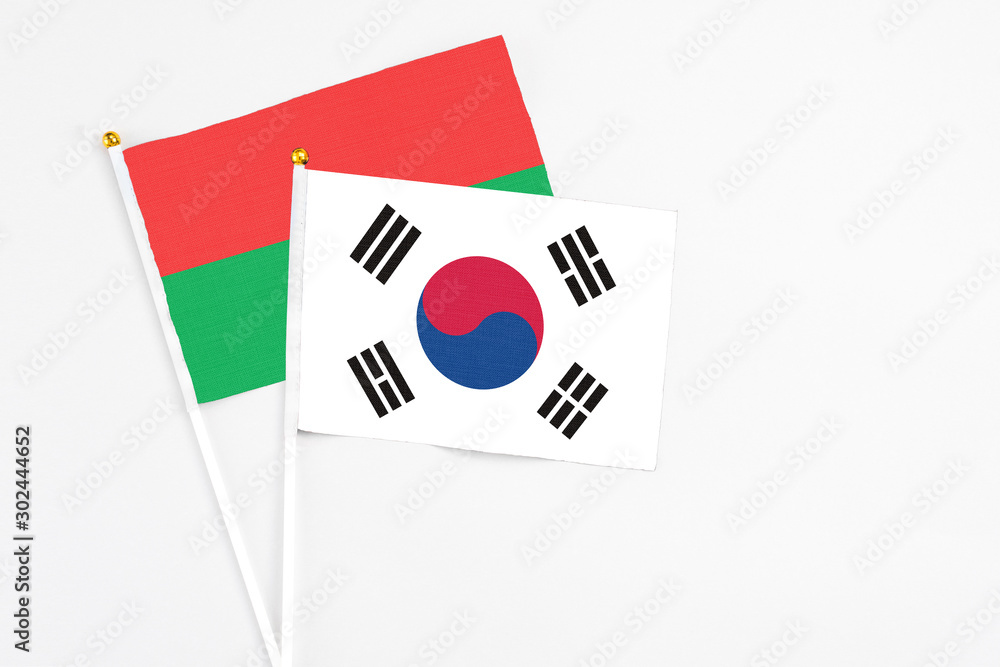 South Korea and Burkina Faso stick flags on white background. High quality fabric, miniature national flag. Peaceful global concept.White floor for copy space.