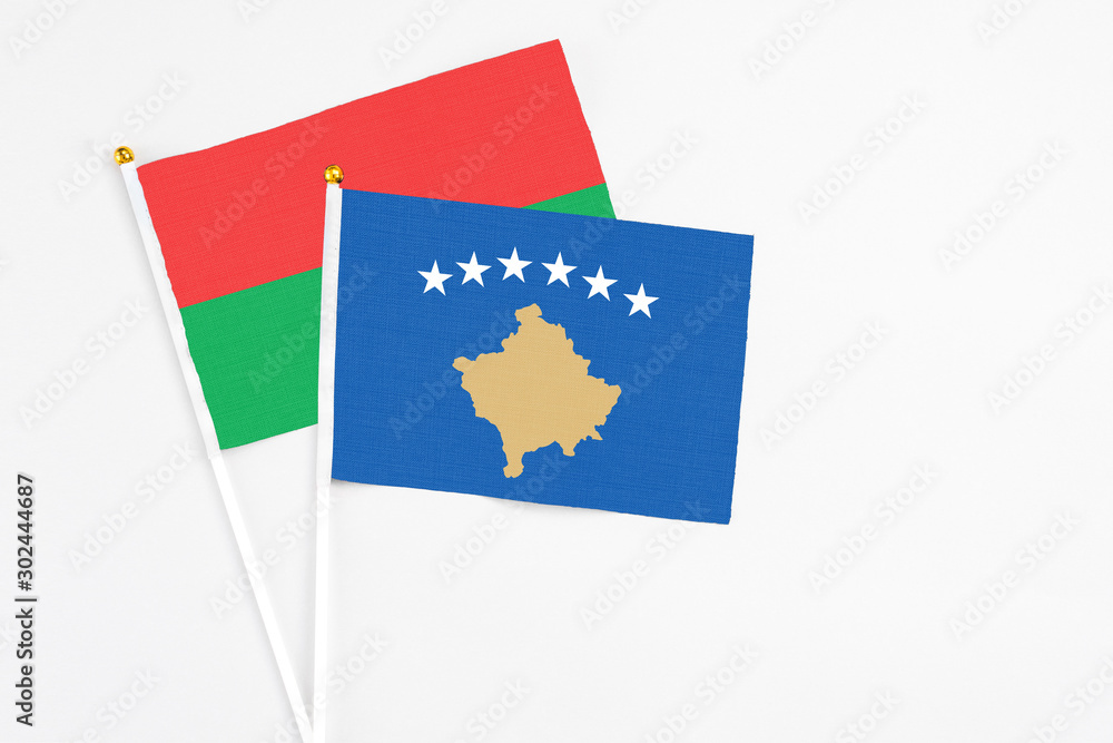 Naklejka premium Kosovo and Burkina Faso stick flags on white background. High quality fabric, miniature national flag. Peaceful global concept.White floor for copy space.