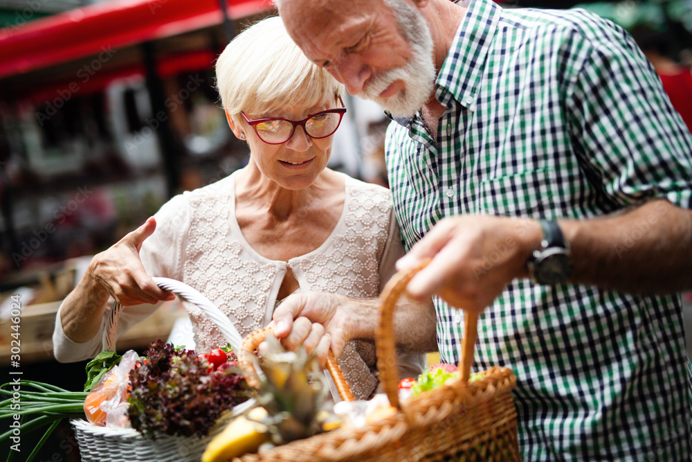 Smiling senior couple holding basket with vegetables at the market Smiling senior couple holding basket with vegetables at the market