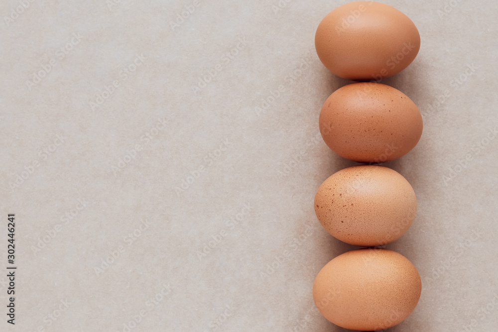 The brown eggs on a neutral paper background. A group of chicken eggs on beige table. Card, frame with text space. The brown eggs on a neutral paper background. A group of chicken eggs on beige table. Card, frame with text space.