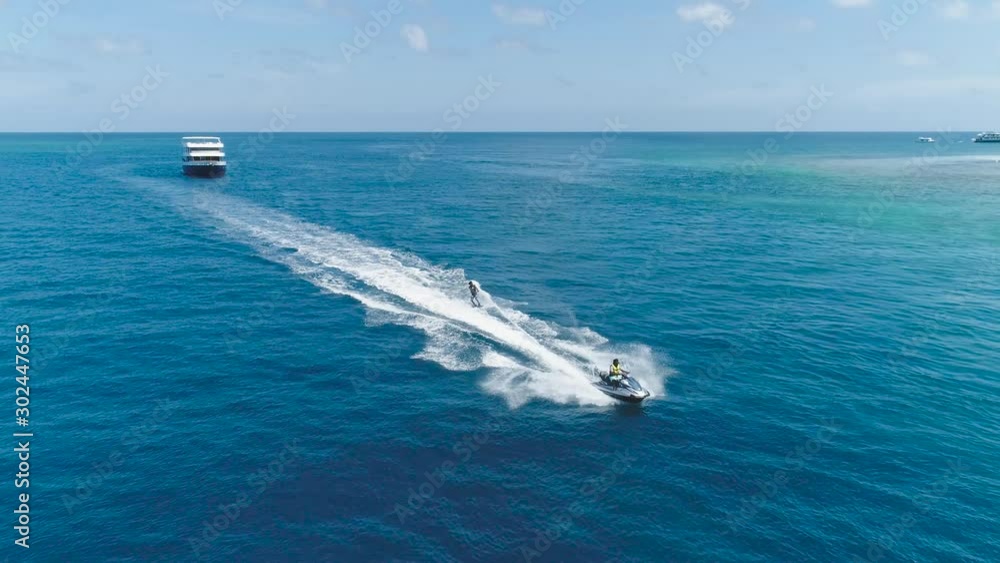 Drone tracking Slow motion shot Over Man Riding Jet Ski At Tropical Paradise Exotic Island with blue and turquoise ocean sea view. Adventure Concept for Tourist Attraction at Beach Vacation at Summer Drone tracking Slow motion shot Over Man Riding Jet Ski At Tropical Paradise Exotic Island with blue and turquoise ocean sea view. Adventure Concept for Tourist Attraction at Beach Vacation at Summer
