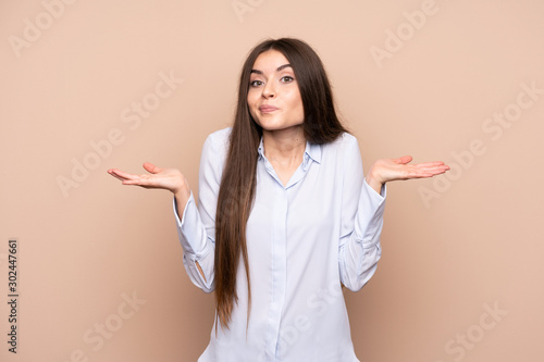 Young woman over isolated background having doubts while raising hands