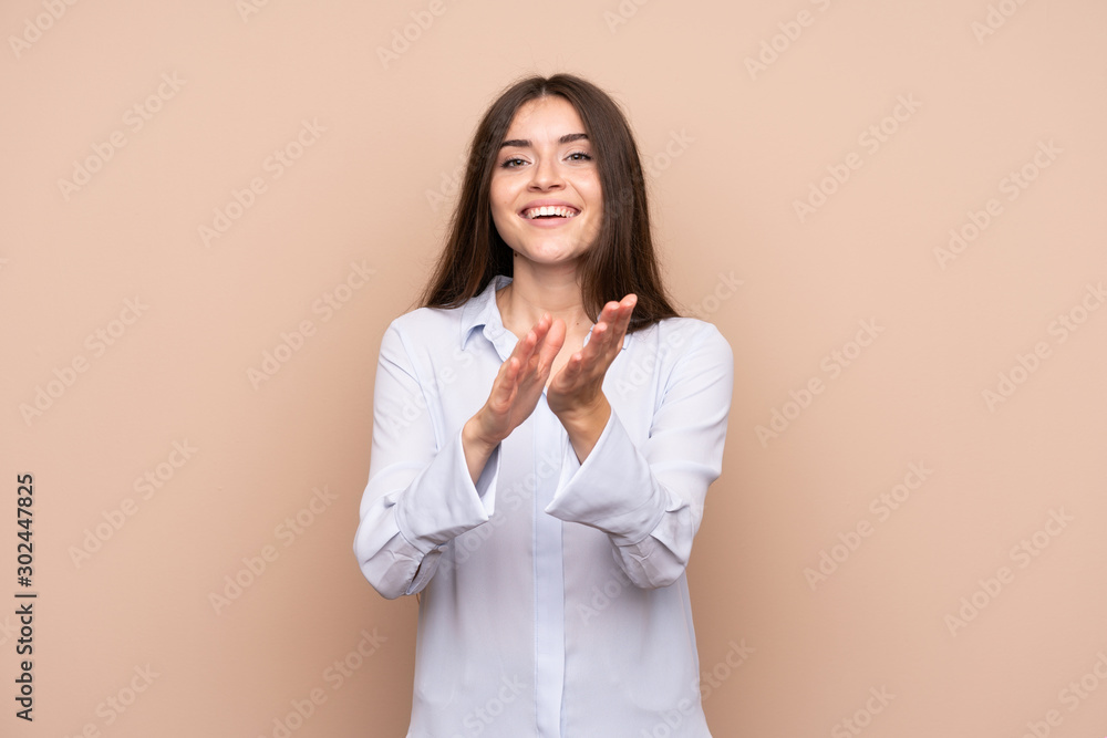 Young woman over isolated background applauding after presentation in a conference Young woman over isolated background applauding after presentation in a conference