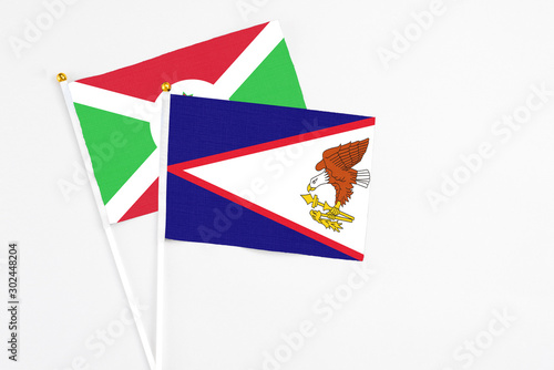 American Samoa and Burundi stick flags on white background. High quality fabric, miniature national flag. Peaceful global concept.White floor for copy space.
