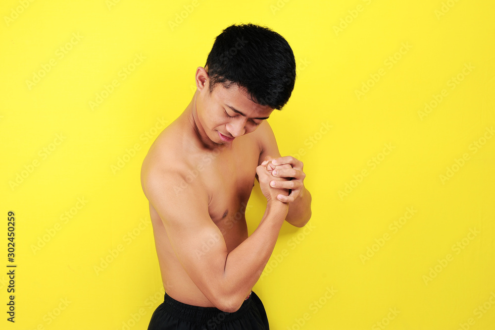 Portrait of Asian man showing the muscles of his arms. Happy Young Asian  Man Showing Muscle over yellow
