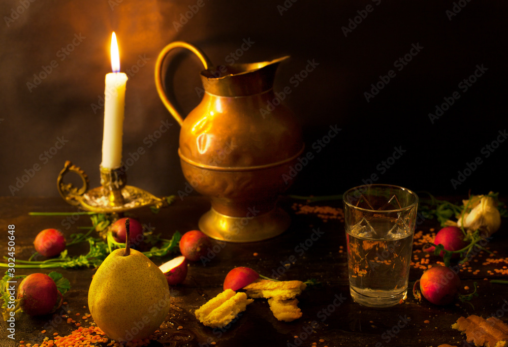 Pear and glass of water with candle on dark table. Still life