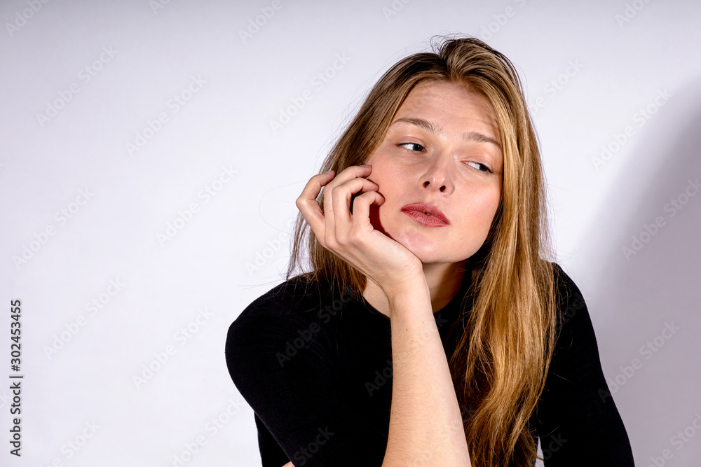 young beautiful blonde girl with a pensive look on a light background young beautiful blonde girl with a pensive look on a light background