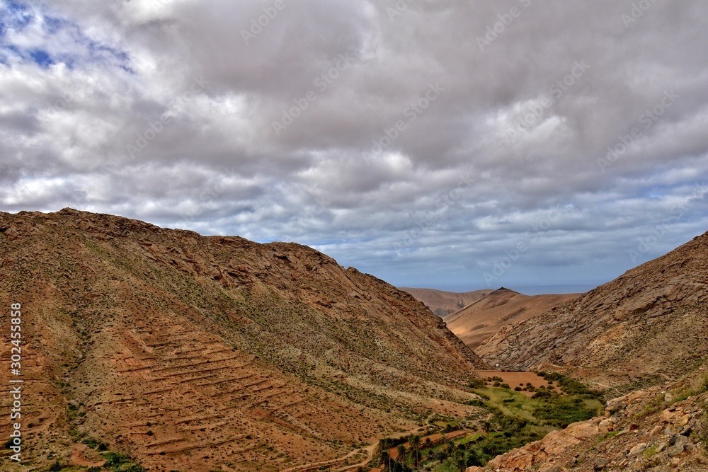 empty mysterious mountainous landscape from the center of the Canary Island Spanish Fuerteventura with a cloudy sky empty mysterious mountainous landscape from the center of the Canary Island Spanish Fuerteventura with a cloudy sky