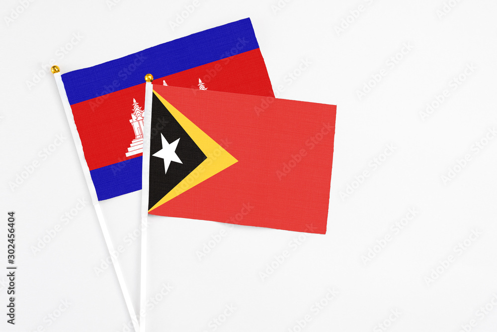 East Timor and Cambodia stick flags on white background. High quality fabric, miniature national flag. Peaceful global concept.White floor for copy space. East Timor and Cambodia stick flags on white background. High quality fabric, miniature national flag. Peaceful global concept.White floor for copy space.
