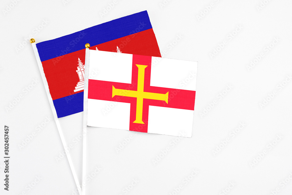 Guernsey and Cambodia stick flags on white background. High quality fabric, miniature national flag. Peaceful global concept.White floor for copy space.