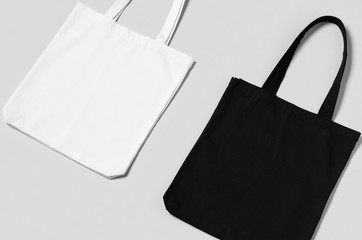 White and black tote bags mockup on a grey background.