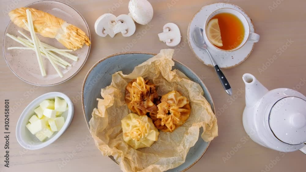 Julienne baked in dough served on a plate on baker paper with tea and butter