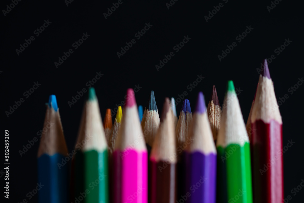 Coloured pencils isolated on black background close up. Vintage look Macro photography. Pencils Wallpaper. Bundle of rainbow colored pencils with selected focus on tips. Multicolored rainbow pencils.
