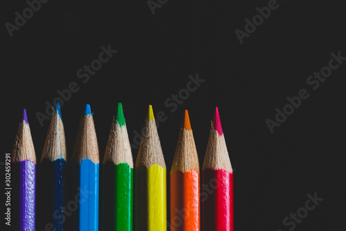 Coloured pencils isolated on black background close up. Vintage look Macro photography. Pencils Wallpaper. Bundle of rainbow colored pencils with selected focus on tips. Multicolored rainbow pencils.