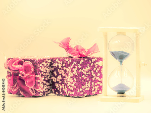 Vintage and crossed process tone of pink gift boxes and hourglass on pastel yellow color background. Special event, birthday, party, celebration or anniversary concepts and ideas. © penkanya