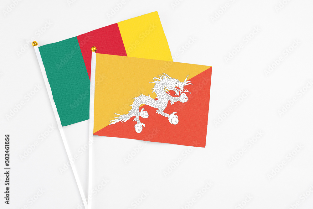 Bhutan and Cameroon stick flags on white background. High quality fabric, miniature national flag. Peaceful global concept.White floor for copy space. Bhutan and Cameroon stick flags on white background. High quality fabric, miniature national flag. Peaceful global concept.White floor for copy space.