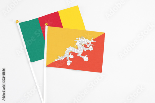 Bhutan and Cameroon stick flags on white background. High quality fabric, miniature national flag. Peaceful global concept.White floor for copy space.