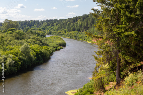 Beautiful summer landscape with green meadows, blue sky, sun and a river