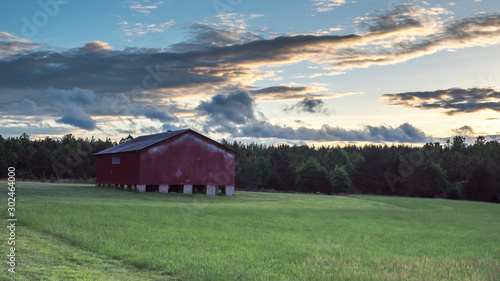 Red barn in a field with sky and clouds in the background