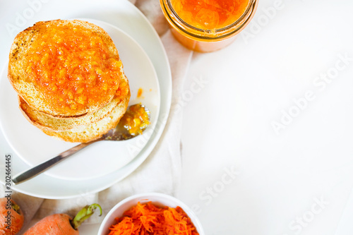 Vegetarian organic sweet carrot jam or marmalade toast topping for breakfast.Healthy vegetable dessert on white background with copy space. top viewHorizontal orientation photo