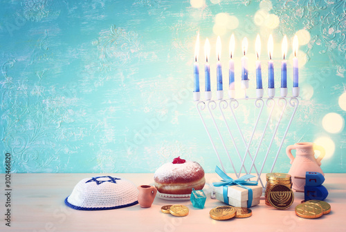 religion image of jewish holiday Hanukkah background with menorah (traditional candelabra), spinning top and doughnut over pastel blue background
