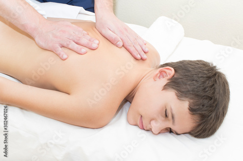 Medical sports massage of the feet of a boy in a massage room on a white background.