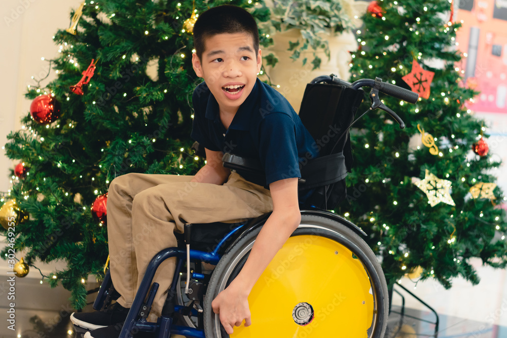 Disabled child on wheelchair with Blurry lights and decorations on the Christmas  tree, Special children's lifestyle, Life in the education age of special  need kids, Happy disability kid concept. Stock Photo