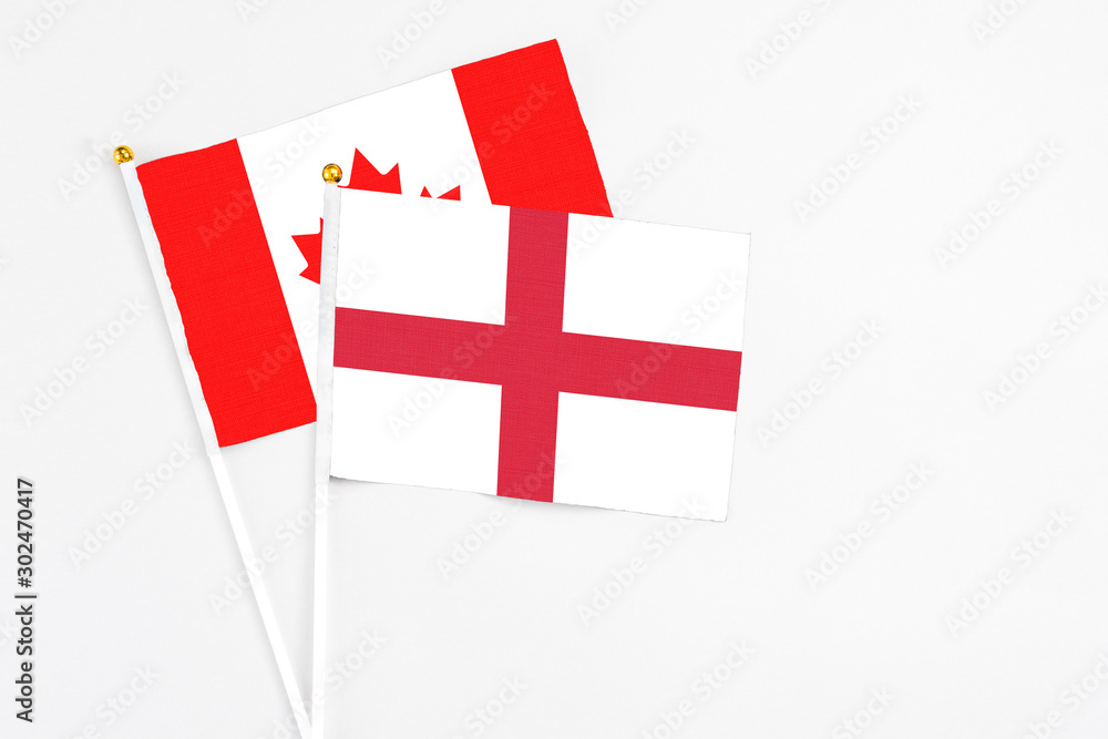 England and Canada stick flags on white background. High quality fabric, miniature national flag. Peaceful global concept.White floor for copy space.